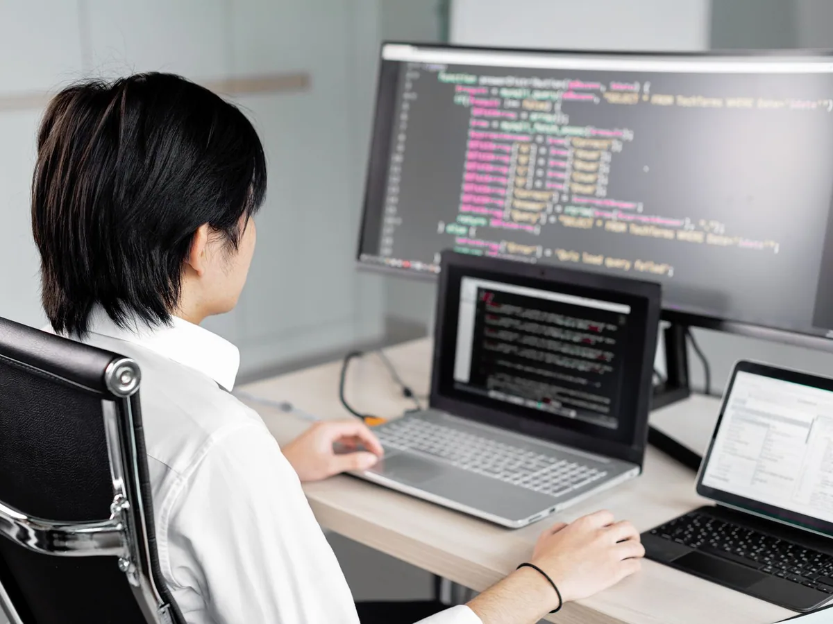 Developer reviewing code on multiple computer screens