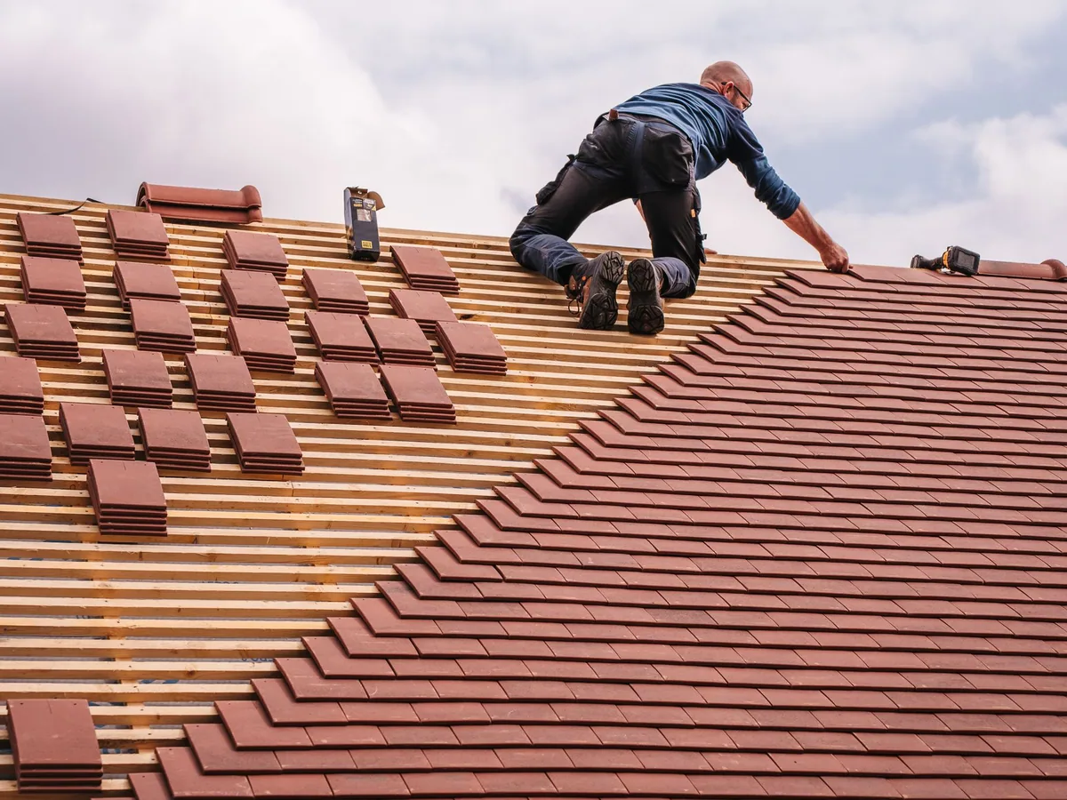 Roofer installing tiles on a residential roof